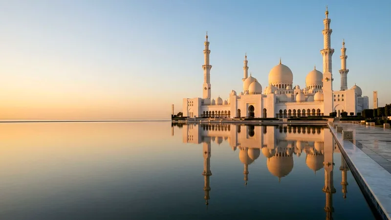 Sheikh Zayed Grand Mosque white domes reflected in pools at golden hour